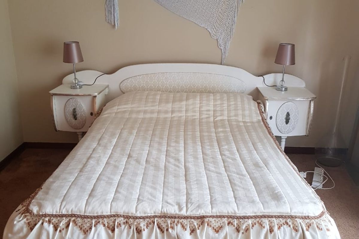 A bedroom featuring neutral wall tones, carpeted flooring, and a built-in headboard with integrated bedside cabinetry.
