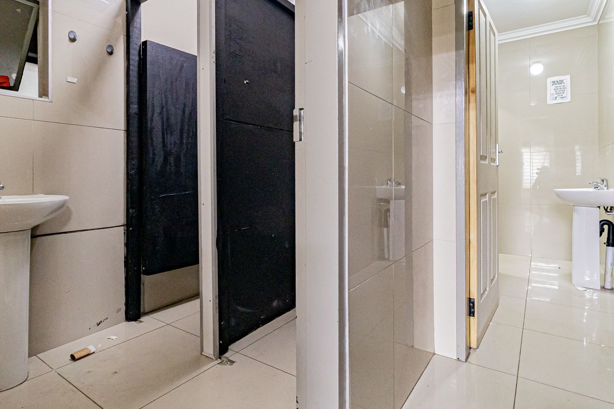 A functional commercial restroom facility featuring tiled walls, pedestal basins, and multiple partitioned cubicles.