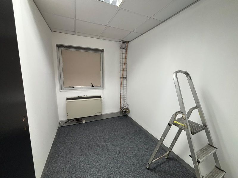 A vacant office space featuring carpet flooring, a suspended ceiling, an HVAC unit, and exposed cable management infrastructure.