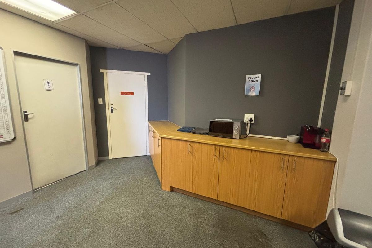 Office kitchenette area featuring built-in wooden cabinetry, grey accent walls, and drop ceiling tiles.