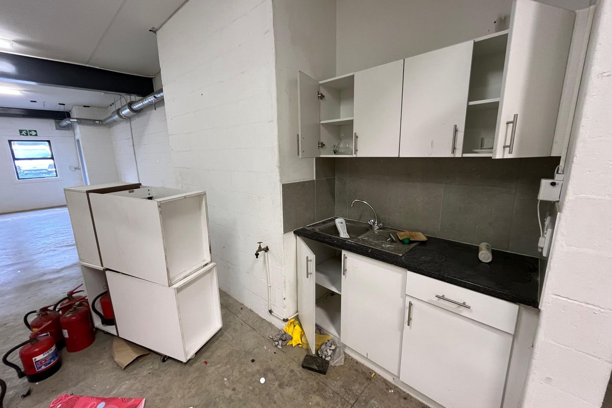 Industrial kitchenette area featuring basic cabinetry, a sink, and exposed structural elements, suitable for a functional workspace or utility area.