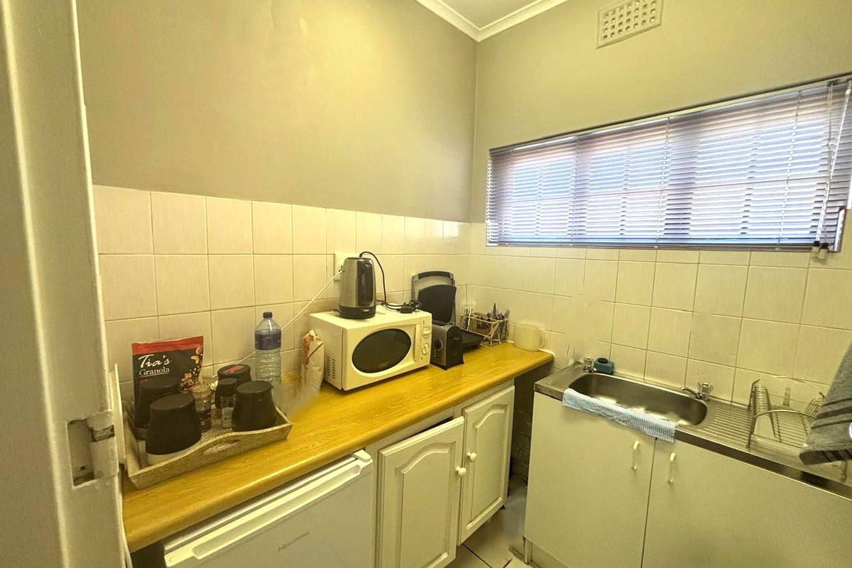 A compact kitchenette featuring tiled splashbacks, a stainless steel sink, and built-in cabinetry with a laminate countertop.