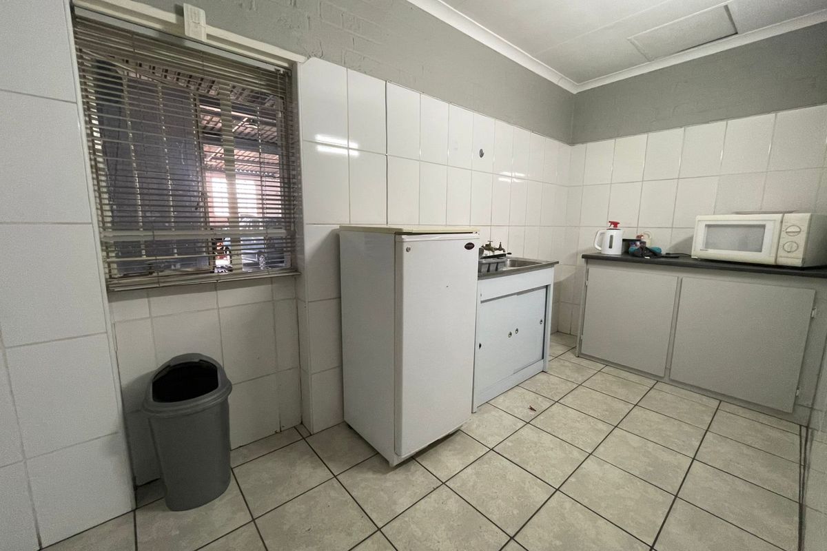 A functional kitchen area featuring tiled walls, basic cabinetry, and a stainless steel sink, offering a practical space for industrial or utility use.