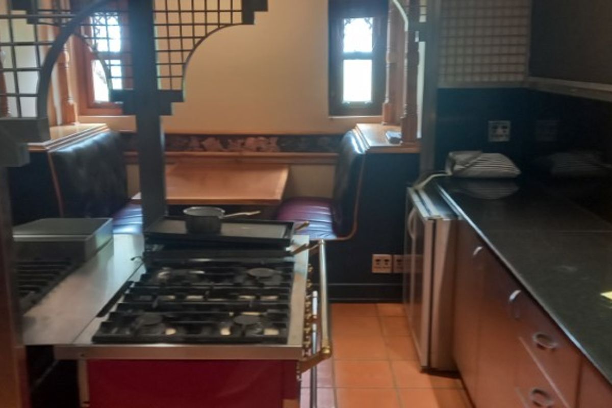 A commercial-style kitchen area featuring a built-in gas range, dark stone countertops, and integrated booth seating with wooden accents.
