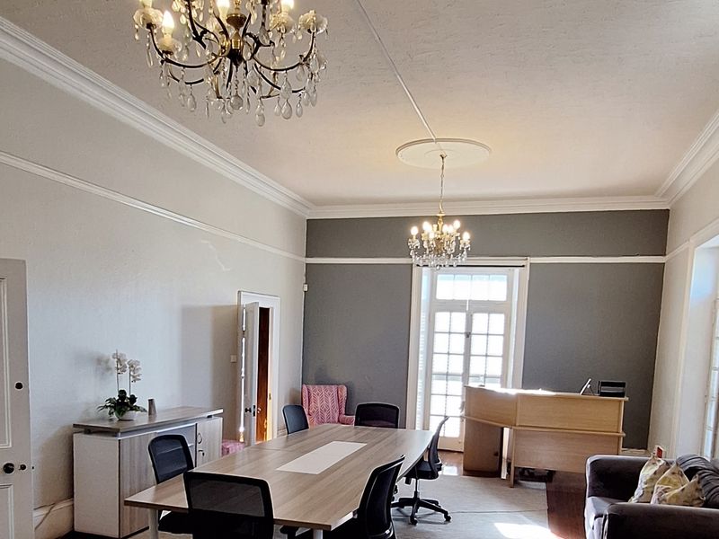 Spacious office area featuring classic architectural details including crystal chandeliers, ceiling roses, picture rails, and polished timber flooring.