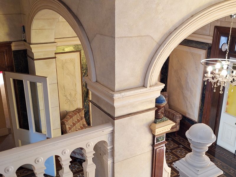 Elegant commercial entrance hall featuring classic arched architecture, decorative columns, a grand chandelier, and ornate tiled flooring.