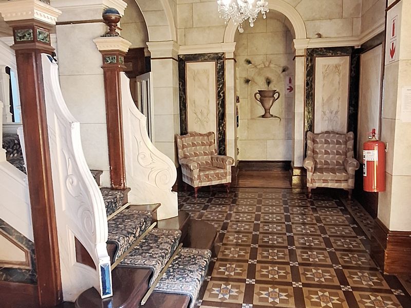 Grand entrance hall featuring intricate patterned floor tiles, arched architectural features, and a decorative timber staircase, creating a sophisticated and welcoming commercial space.