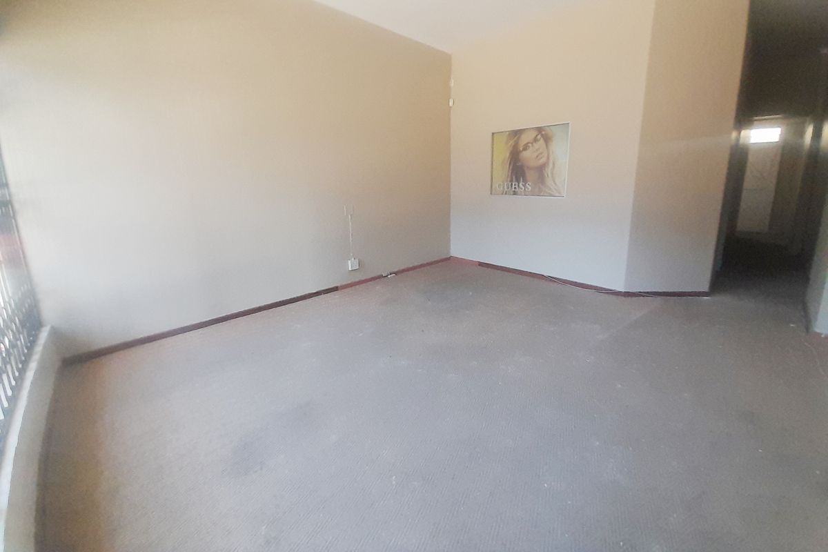 An empty, open-plan retail space featuring neutral walls and worn carpeting, suitable for a variety of commercial business applications.