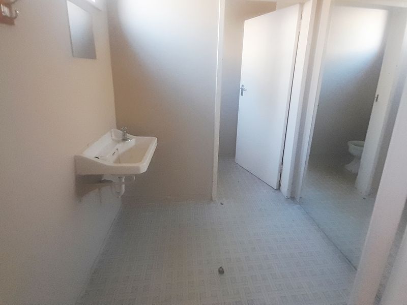 A functional, empty bathroom space featuring a wall-mounted basin and tiled flooring, ready for renovation or modernization.