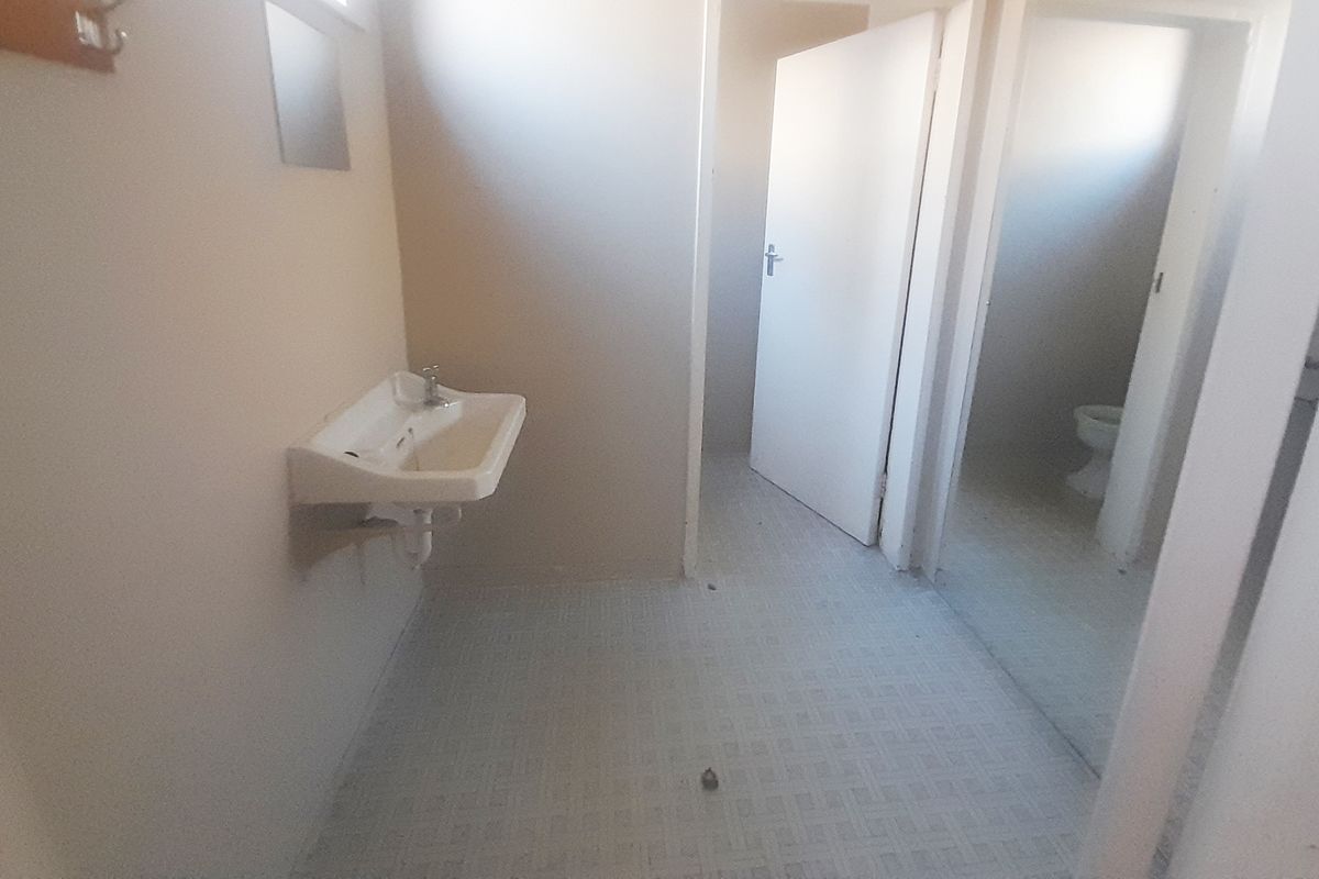 A functional, empty bathroom space featuring a wall-mounted basin and tiled flooring, ready for renovation or modernization.