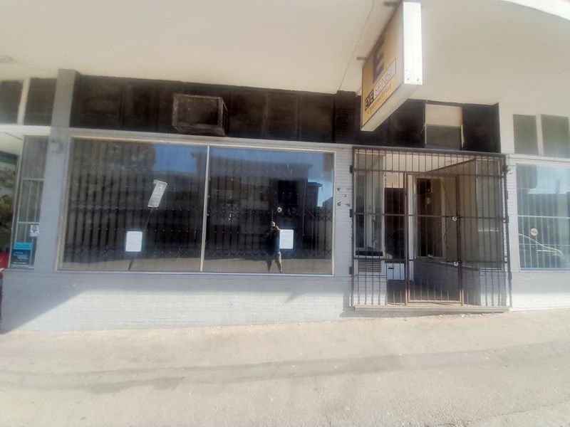 Front facade of a retail shop featuring a large display window and a secure metal entrance gate.