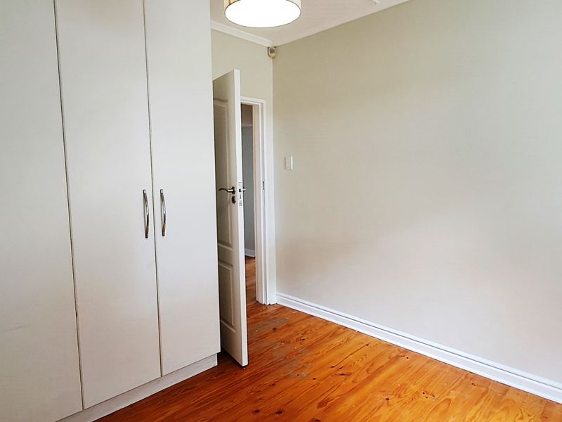 An empty bedroom featuring polished timber flooring and built-in cupboards, offering a clean and neutral space ready for personalization.