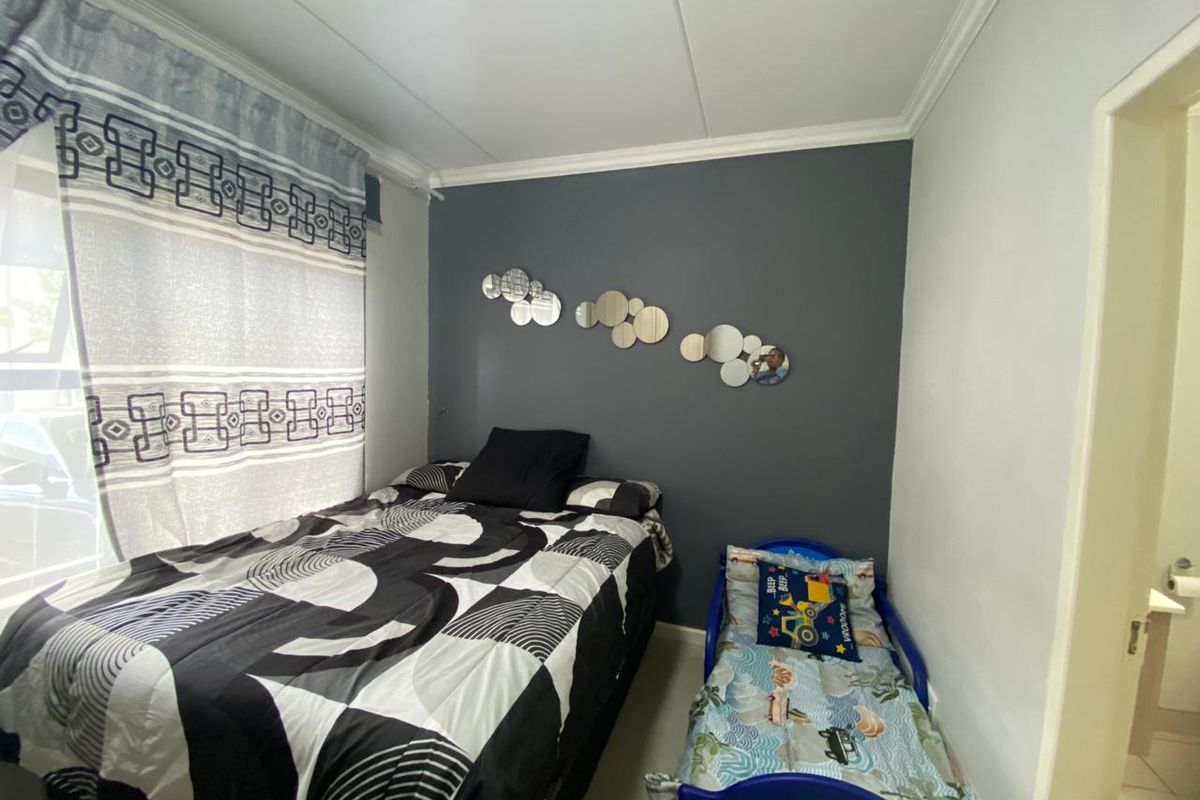 A bedroom featuring a dark grey accent wall, crown molding, and tiled flooring.
