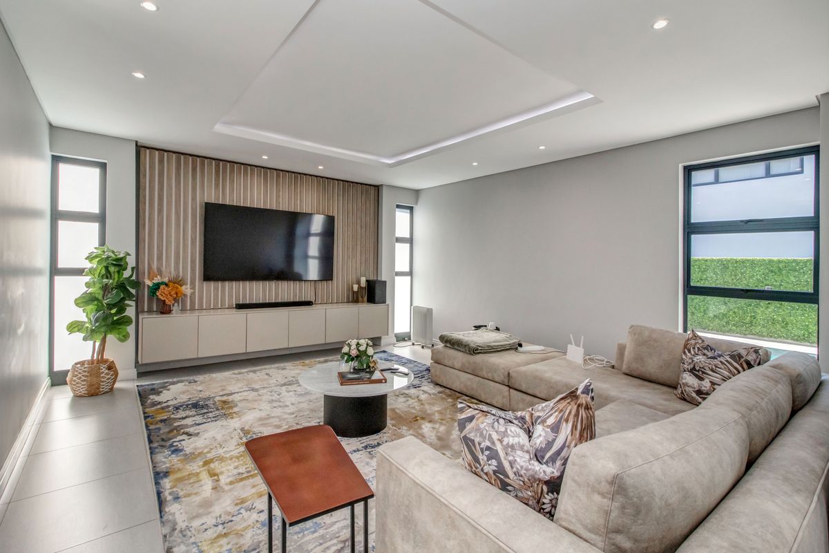 Modern living room featuring a coffered ceiling with recessed lighting, custom slatted wood wall paneling, and sleek built-in cabinetry.