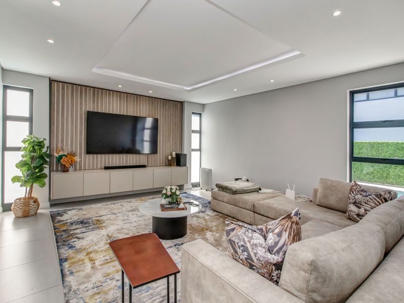 Modern living room featuring a coffered ceiling with recessed lighting, custom slatted wood wall paneling, and sleek built-in cabinetry.