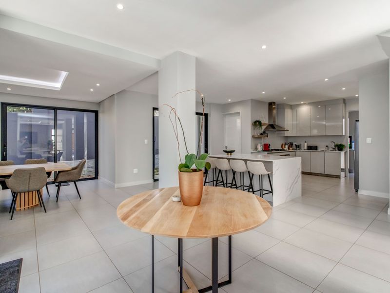 Modern open-plan living area featuring a sleek kitchen with a stone island, recessed lighting, and large sliding doors leading to the outdoor space.