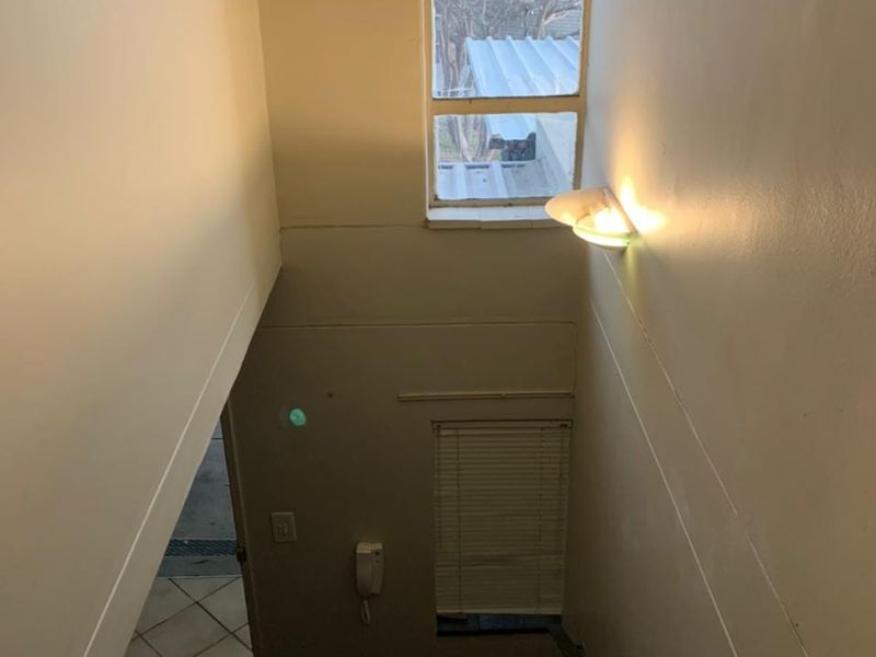 A functional stairwell area featuring a wall-mounted light, intercom system, and window with blinds, providing access between levels.