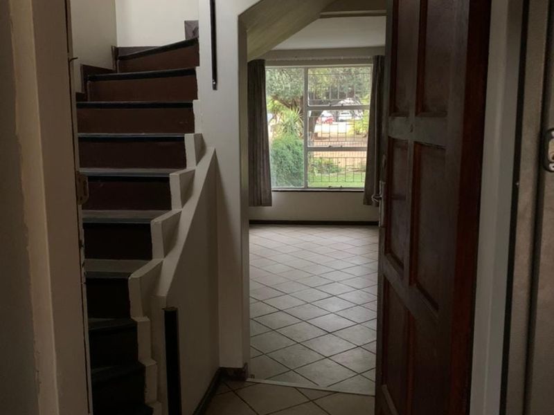 Entrance foyer featuring tiled flooring and a staircase leading to the upper level, providing a clear view into the adjacent living area.
