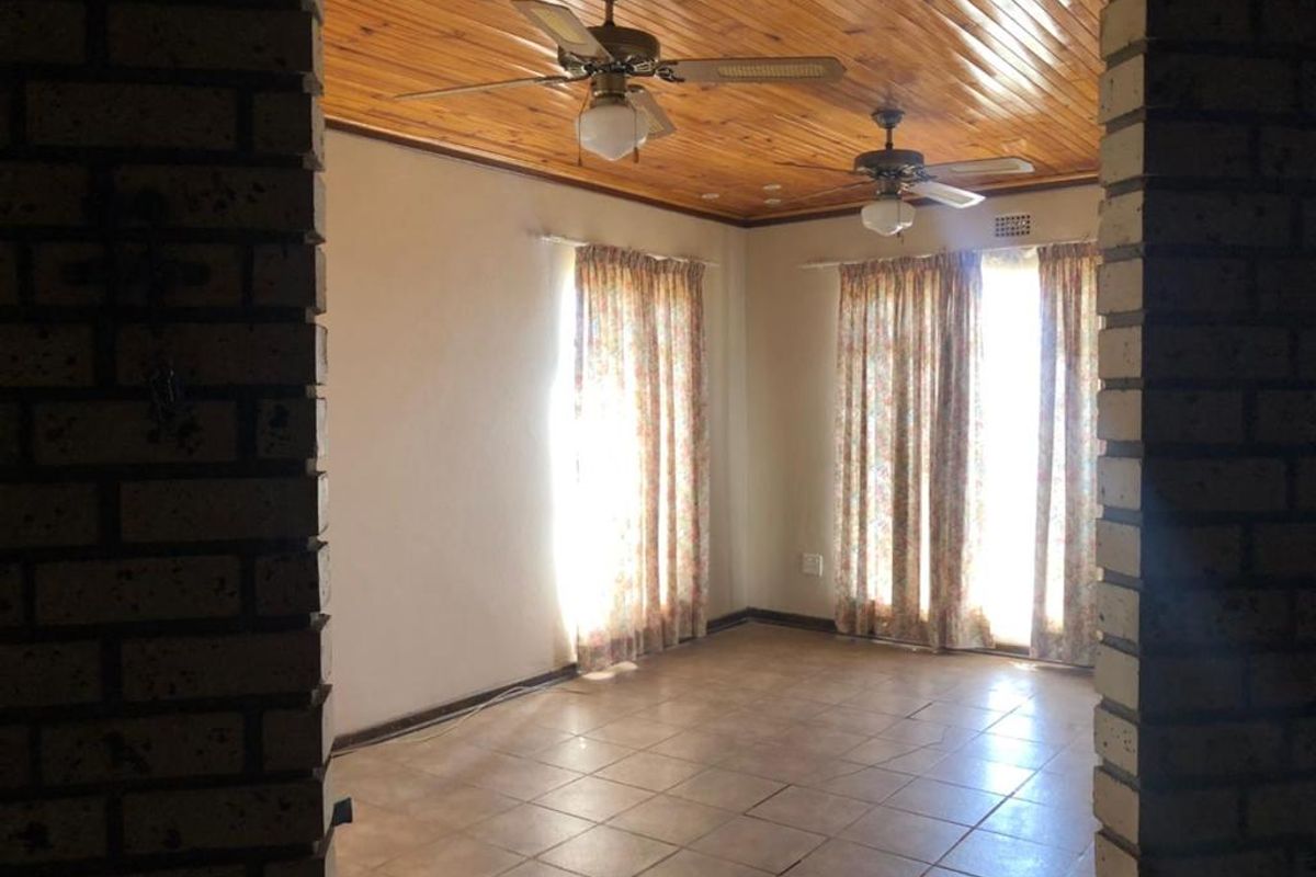 A living room featuring tiled flooring, a timber-paneled ceiling with dual ceiling fans, and brick archway entry.