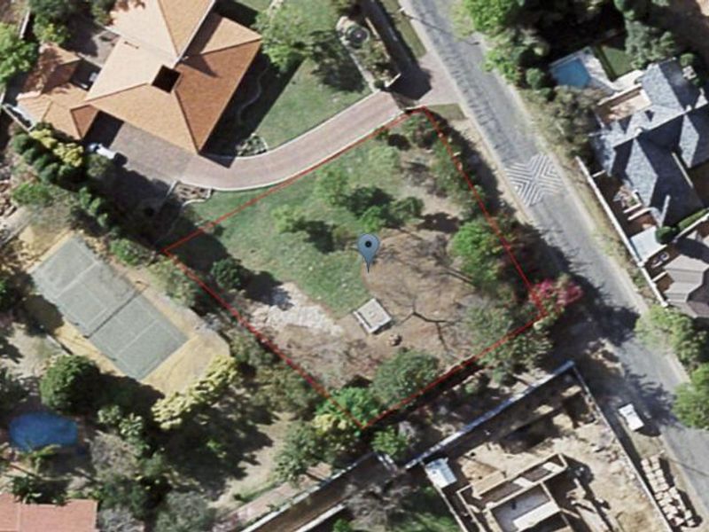 An aerial view of a vacant residential plot, highlighting the property boundaries and surrounding neighborhood context.