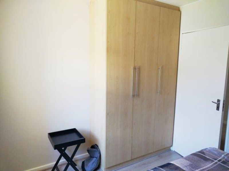 A bedroom featuring a light wood-finish built-in wardrobe and laminate flooring.