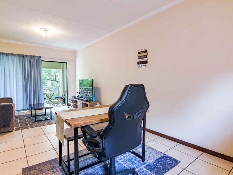 A bright living room featuring tiled flooring and a sliding glass door providing access to an outdoor balcony area.