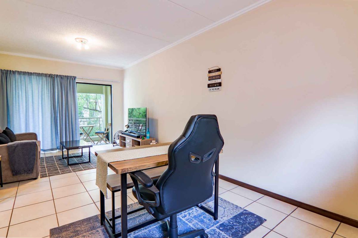 A bright living room featuring tiled flooring and a sliding glass door providing access to an outdoor balcony area.