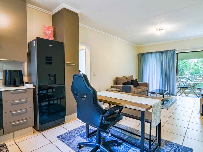 Open-plan living area featuring a modern kitchen with built-in appliances, tiled flooring, and direct access to a private balcony through sliding glass doors.