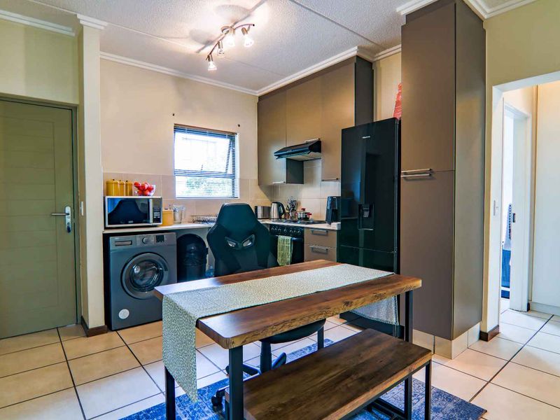 A functional kitchen featuring modern dark cabinetry, tiled flooring, and integrated appliance spaces, offering a practical layout for daily cooking and dining.