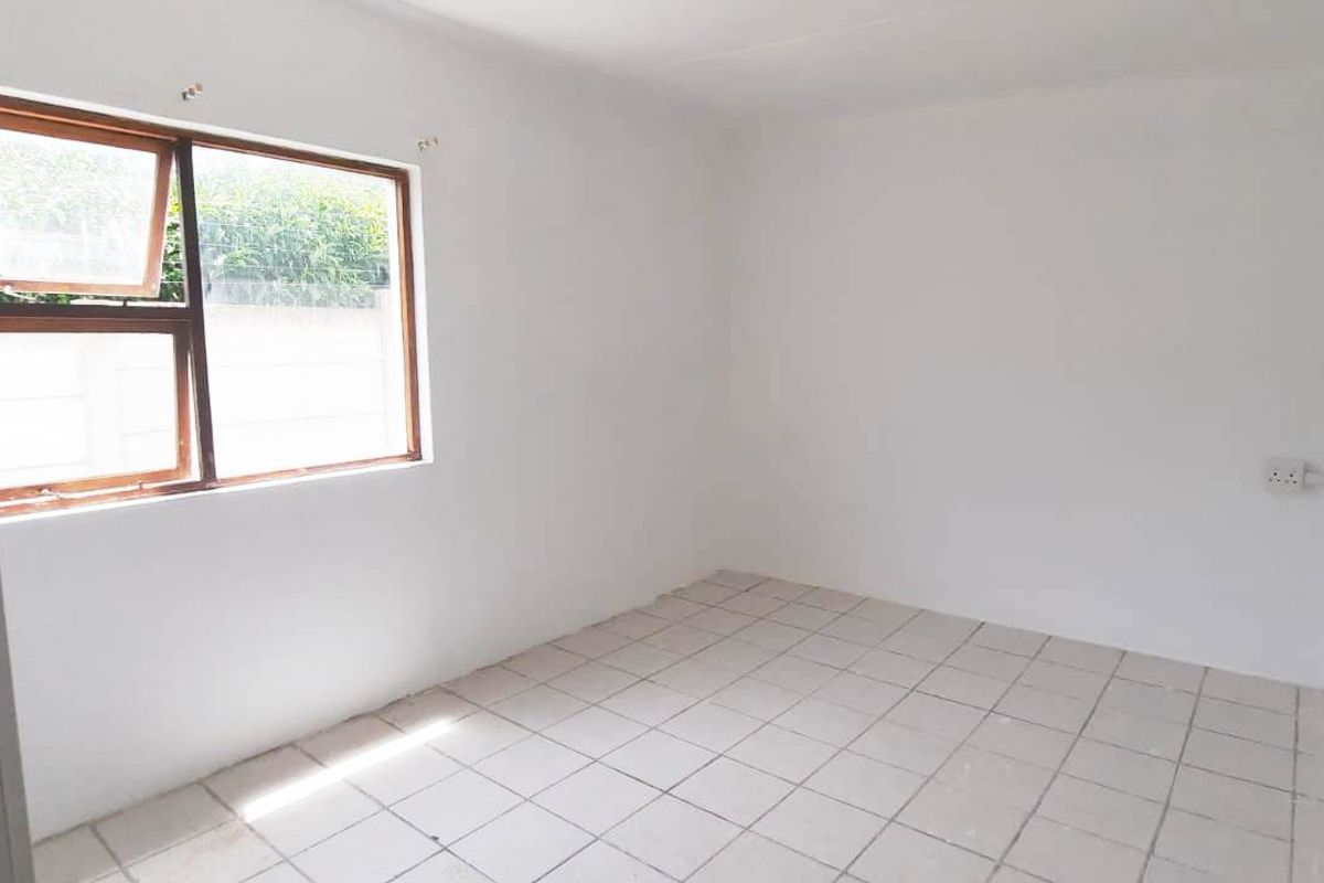 An empty bedroom featuring tiled flooring and a window with an aluminium frame, offering a blank canvas for potential interior design.