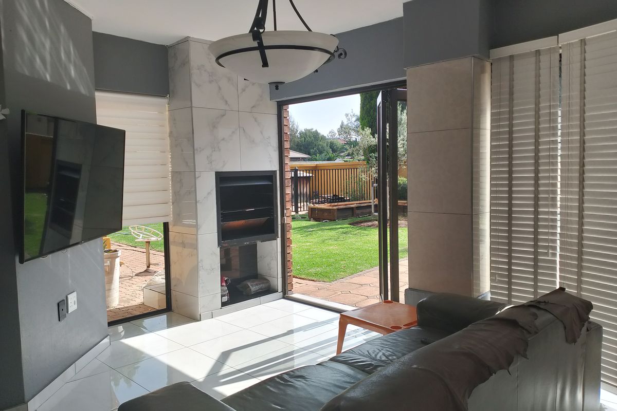 A bright living room featuring a modern built-in fireplace with marble-effect tiling, large glass sliding doors, and direct access to the rear garden.