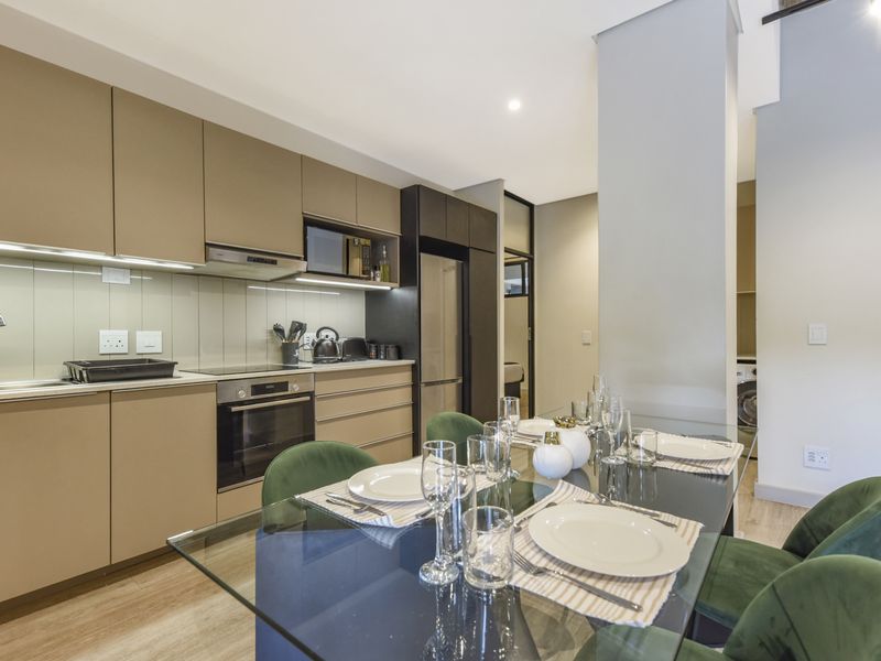Modern open-plan kitchen and dining area featuring sleek cabinetry, integrated appliances, and high-quality finishes, creating a functional and contemporary living space.