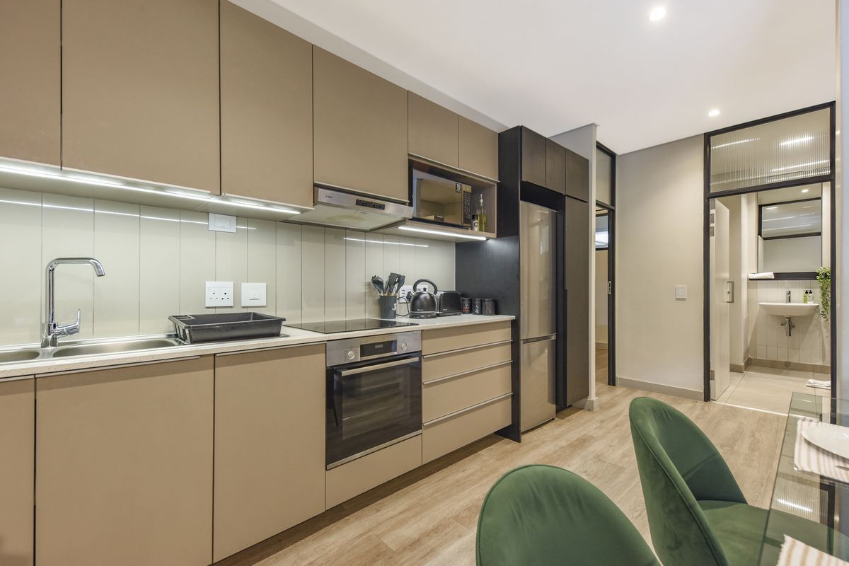 Modern kitchen featuring sleek handleless cabinetry, integrated appliances, electric hob, and a clean, contemporary aesthetic with wood-look flooring.