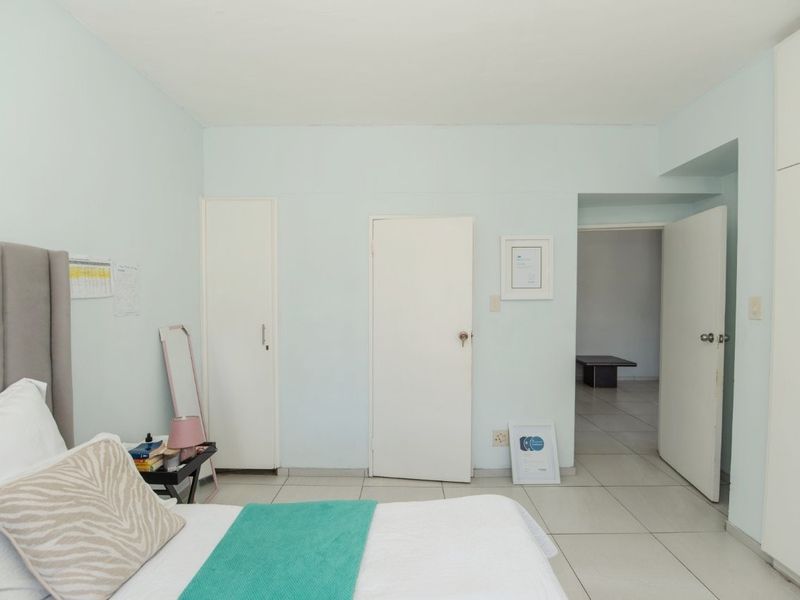 A bedroom featuring tiled flooring and built-in cupboards, with an open doorway leading to an adjacent room.