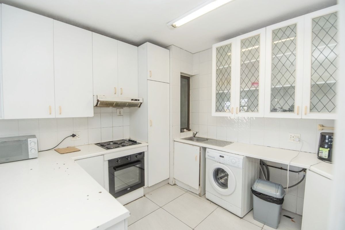 Functional kitchen featuring white cabinetry, built-in oven and hob, tiled splashbacks, and dedicated plumbing for a washing machine.