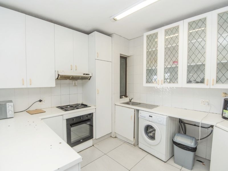 Functional kitchen featuring white cabinetry, built-in oven and hob, tiled splashbacks, and dedicated plumbing for a washing machine.