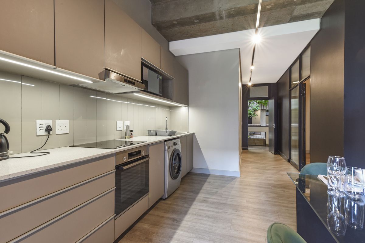 Modern kitchen featuring sleek cabinetry, stone countertops, integrated appliances, and an exposed concrete ceiling, creating a contemporary and functional culinary space.