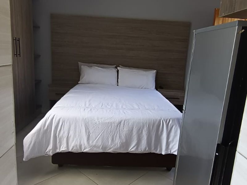 A bedroom featuring built-in wardrobes, a headboard, and tiled flooring, providing a functional and well-maintained living space.