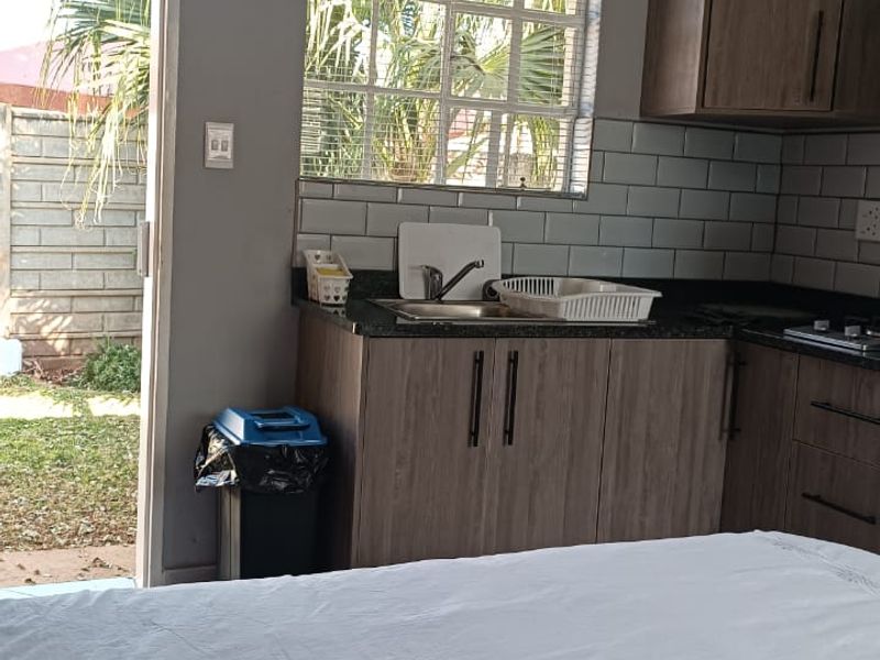 Open plan kitchen area featuring modern wood-finish cabinetry, subway tile backsplash, and direct access to the outdoor garden space.