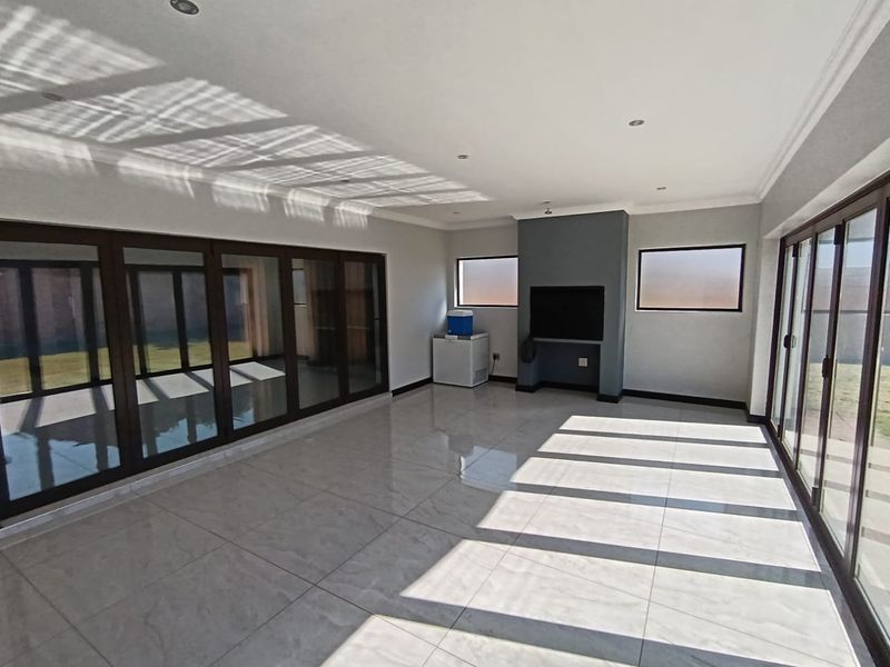Spacious, light-filled living area featuring large sliding glass doors, polished tile flooring, and a modern built-in fireplace, offering a clean, contemporary aesthetic.