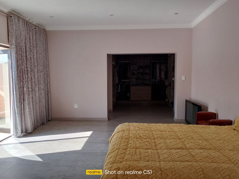 Spacious bedroom featuring tiled flooring, recessed lighting, and a large walk-in closet, with direct access to an outdoor area through sliding glass doors.