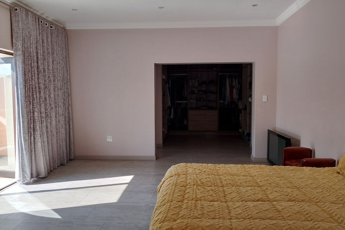 Spacious bedroom featuring tiled flooring, recessed lighting, and a large walk-in closet, with direct access to an outdoor area through sliding glass doors.
