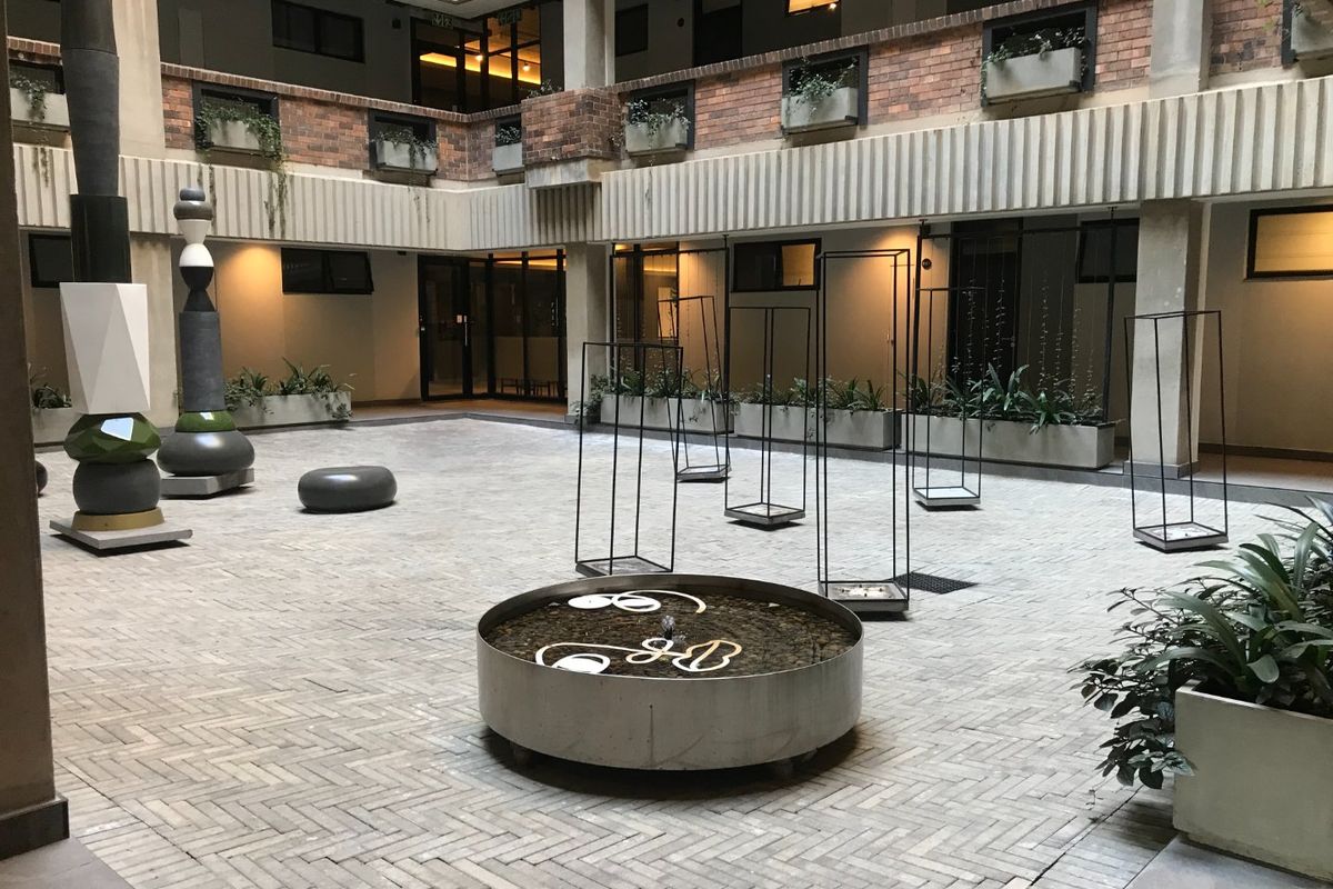 A central courtyard area featuring brick paving, concrete planters, and a circular water feature within an apartment complex.