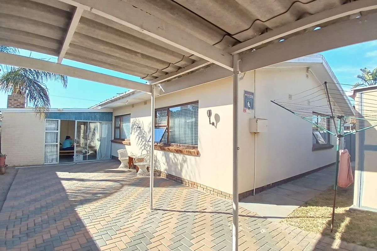 Rear exterior view featuring a paved patio area, a covered carport structure, and access to the home via a sliding glass door.