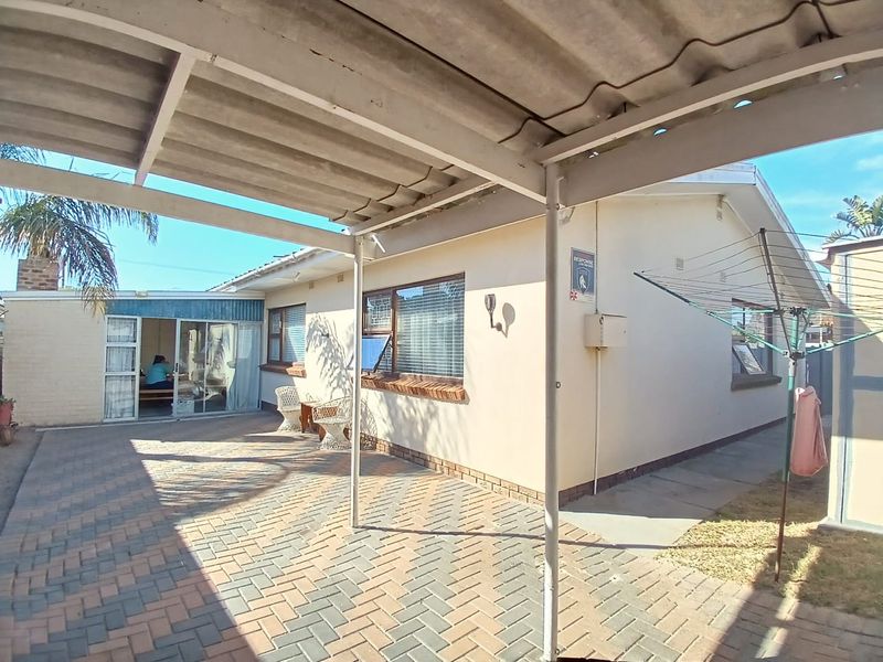 Rear exterior view featuring a paved patio area, a covered carport structure, and access to the home via a sliding glass door.