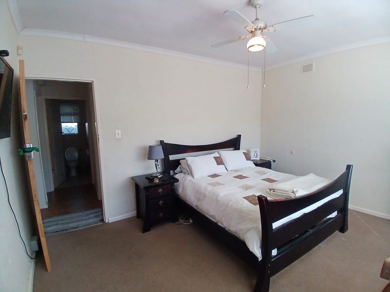 A standard bedroom featuring a ceiling fan and an adjoining en-suite bathroom, providing a functional and neutral living space.