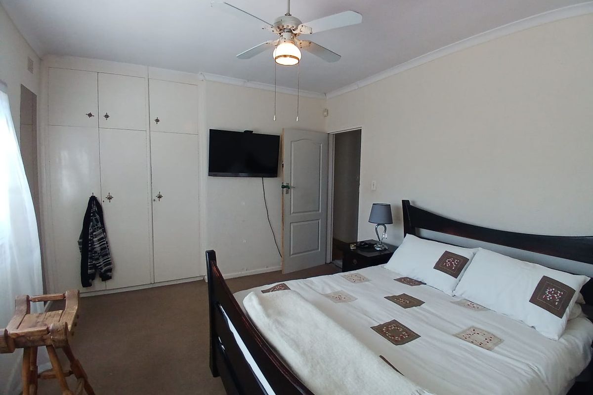 A functional bedroom featuring built-in cupboards, a ceiling fan, and carpeted flooring, offering a neutral space ready for personalization.