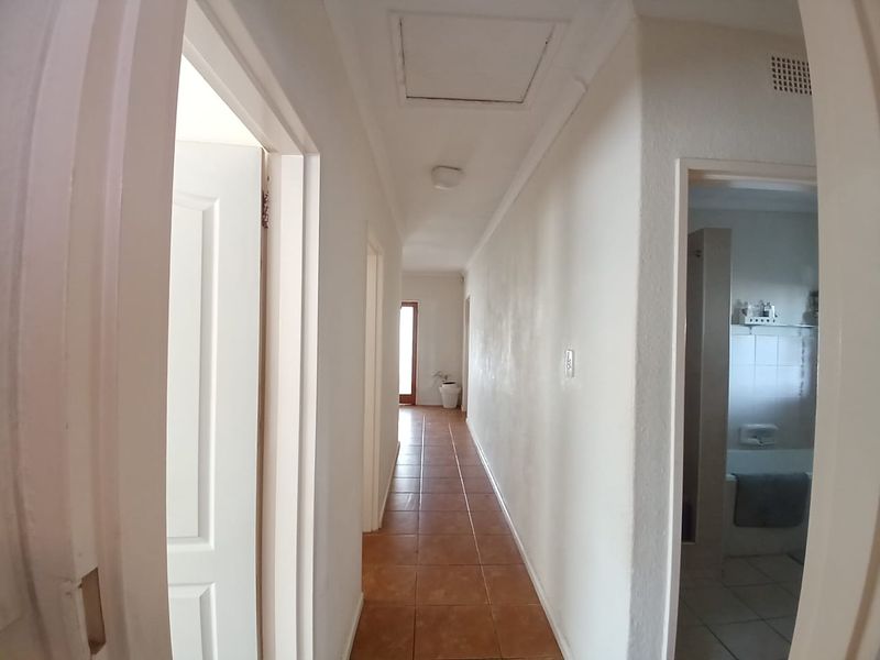 A functional hallway featuring tiled flooring and access to adjacent rooms, including a bathroom, with neutral wall finishes.