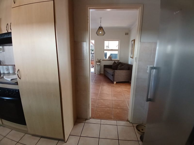 View from the kitchen looking through a doorway into the adjacent living area, featuring tiled flooring and built-in cabinetry.