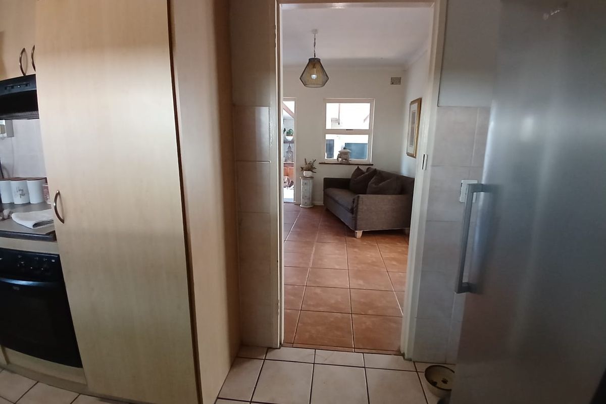 View from the kitchen looking through a doorway into the adjacent living area, featuring tiled flooring and built-in cabinetry.
